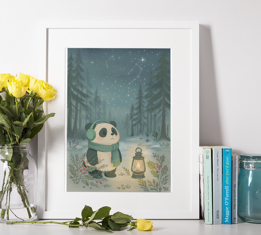 Cozy Winter Nights print framed and displayed on desk with yellow roses and books, showcasing Wonton panda in cozy winter scene