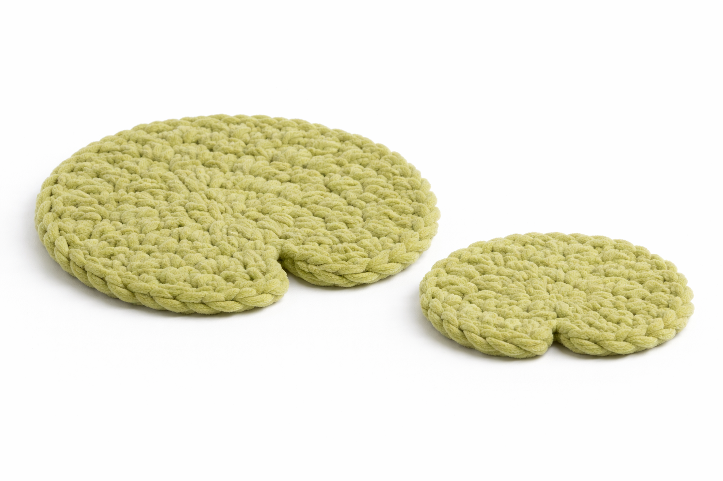 Two handmade crochet lily pads in green plush yarn, one small and one large, on a white background.