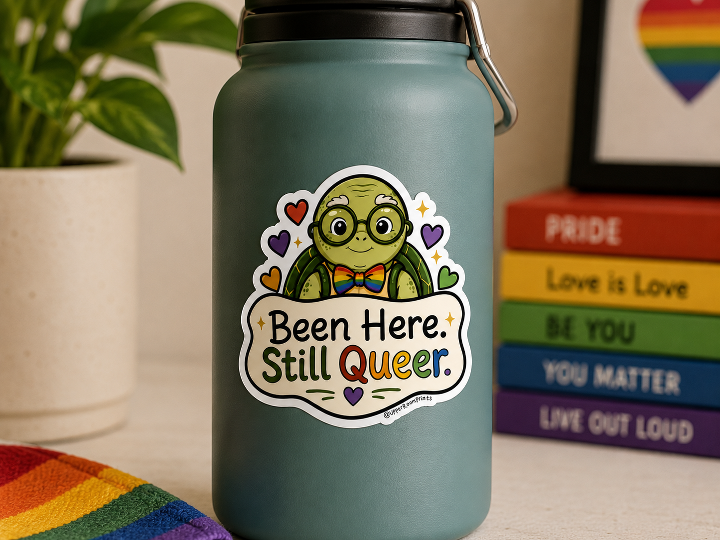 Green water bottle with a sticker featuring a cartoon turtle and text, placed on a surface with books and a plant in the background.