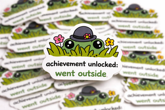 Sticker with a cartoon frog wearing a hat and flowers, surrounded by similar stickers with text.