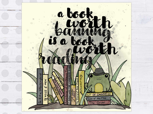 Full view of the Banned Books Print showing Edgar the frog holding a stack of banned book titles in a watercolor style