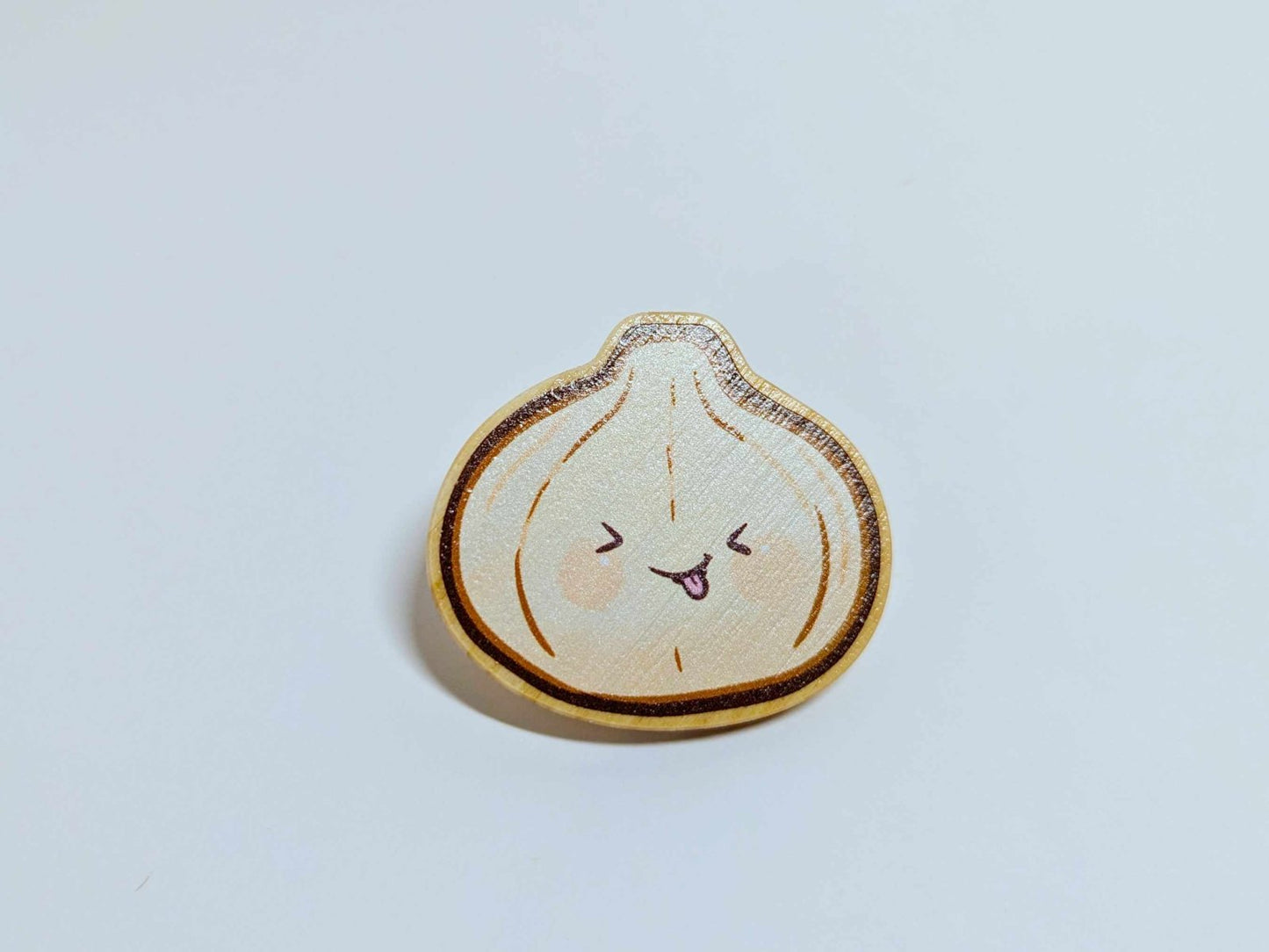Cheesy Dumpling wooden pin – a 1.5-inch handcrafted wood pin featuring a smiling dumpling design, secured with a heart clasp, perfect for food lovers and quirky fashion fans.