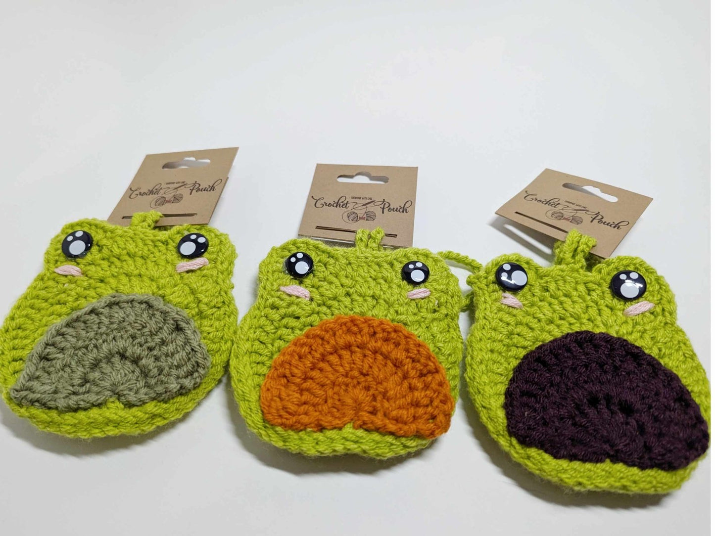 Three handmade crochet Frog Pouch Bag Charms in green with purple, orange, and green tummies displayed together
