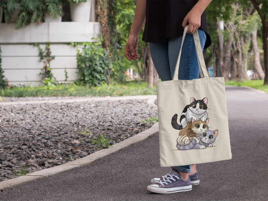 Person holding Kitty Stack cotton tote bag in hand showing size and cat design, reusable shopping bag