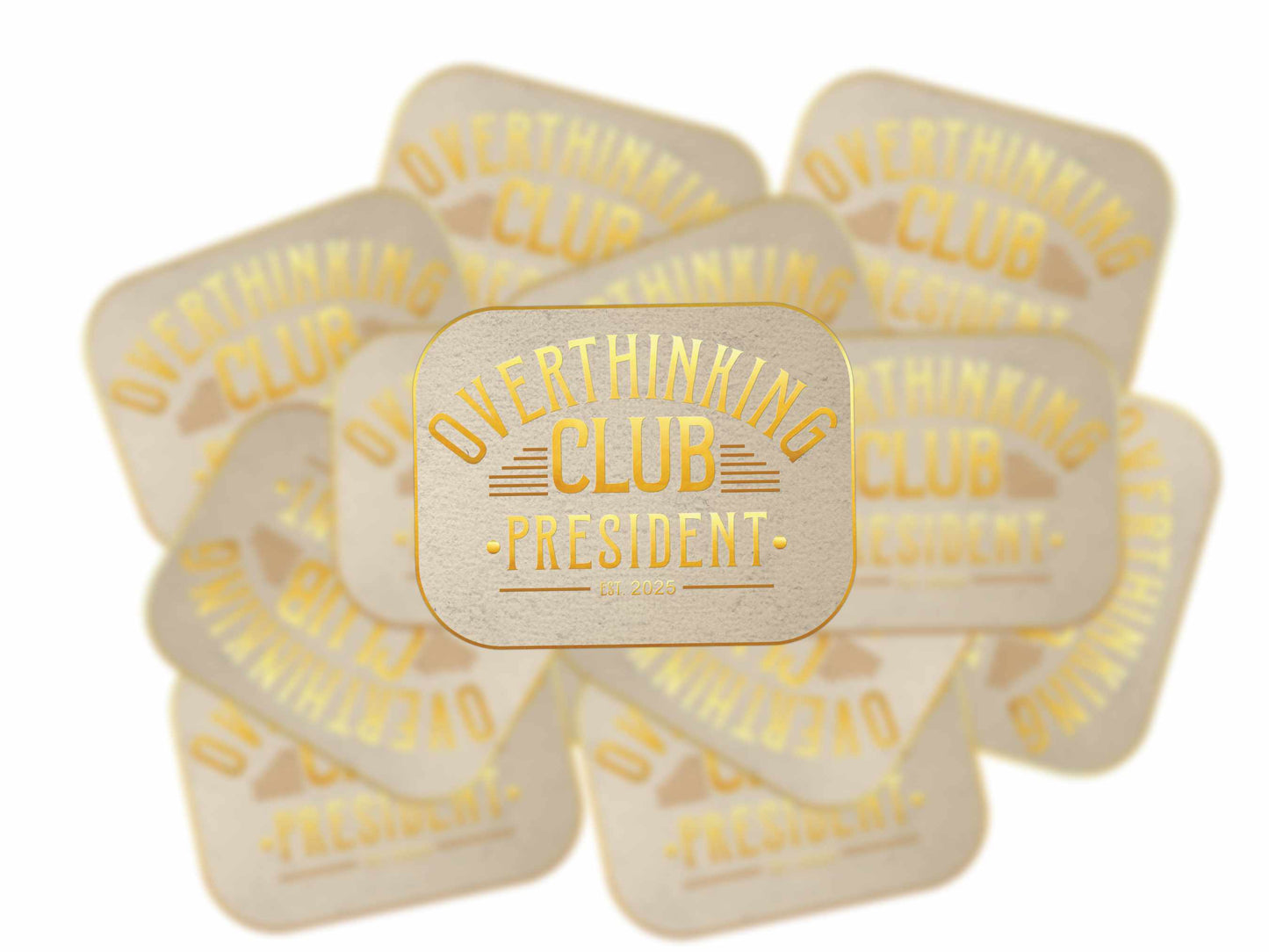 Stack of Overthinking Club President stickers with gold foil design on parchment-style background, one in sharp focus.