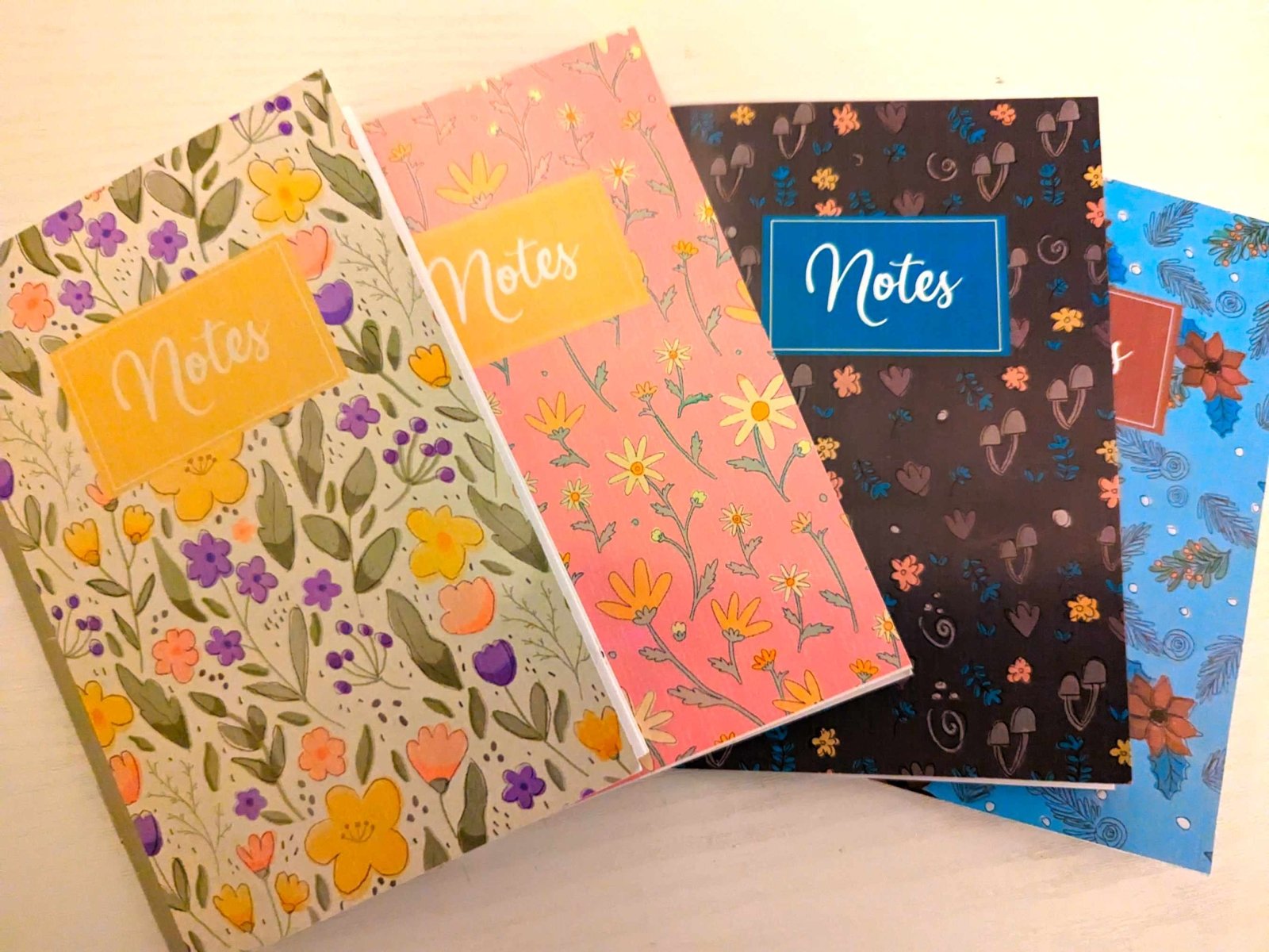 Front-facing image of the four handmade floral notebooks from the Seasons Flowers Notebook Bundle