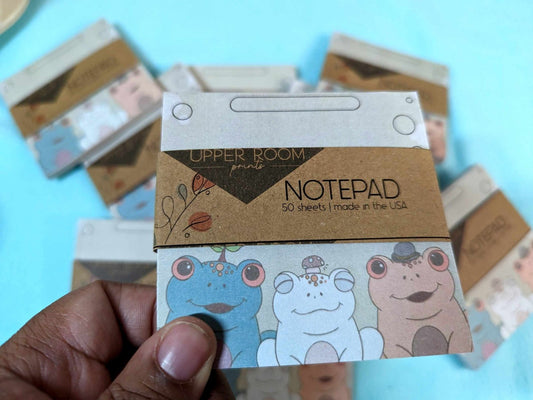 Hand holding 3x3 Trio Frog Notepad featuring illustrated frogs on each sheet for notes or lists.