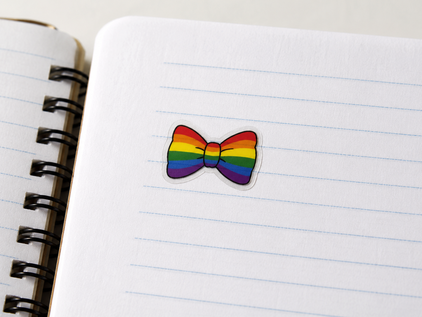 Rainbow bow tie sticker on a lined notebook page