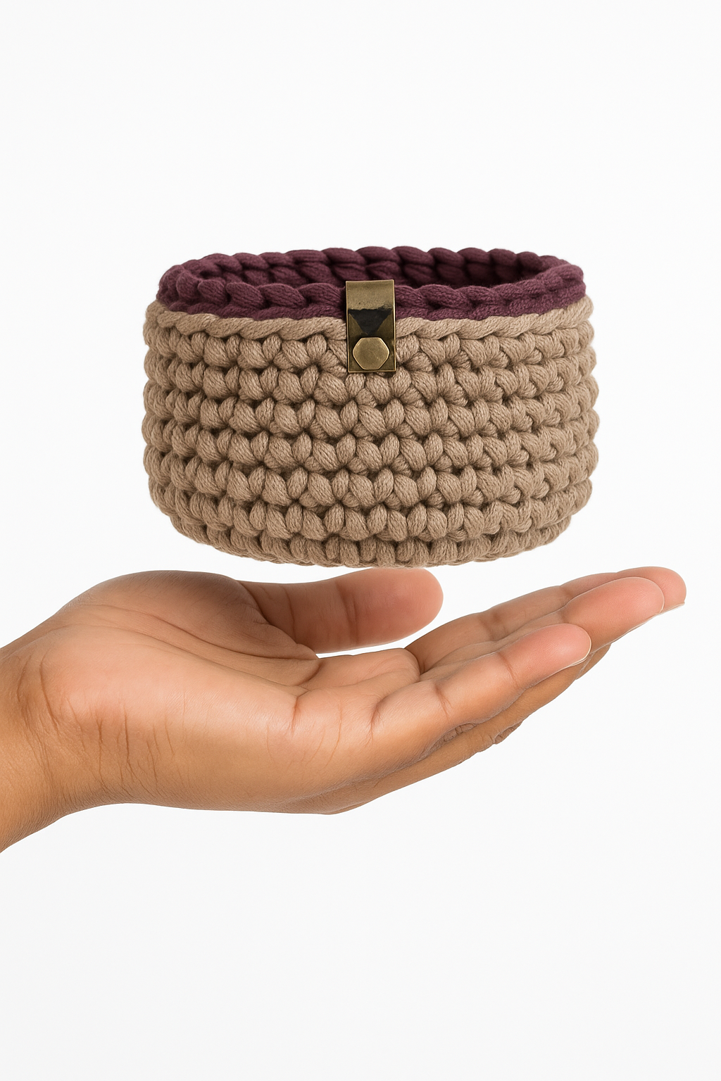 A hand holds a stacked set of six crochet nesting bowls made from chunky cotton yarn. The bowls, ranging in size and color, are displayed vertically to highlight their compact and nested design.