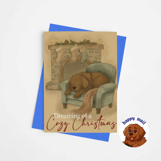 Cozy Christmas greeting card featuring brown dog Fred sleeping in armchair by fireplace with stockings and evergreen garland, cottagecore holiday card with blue envelope
