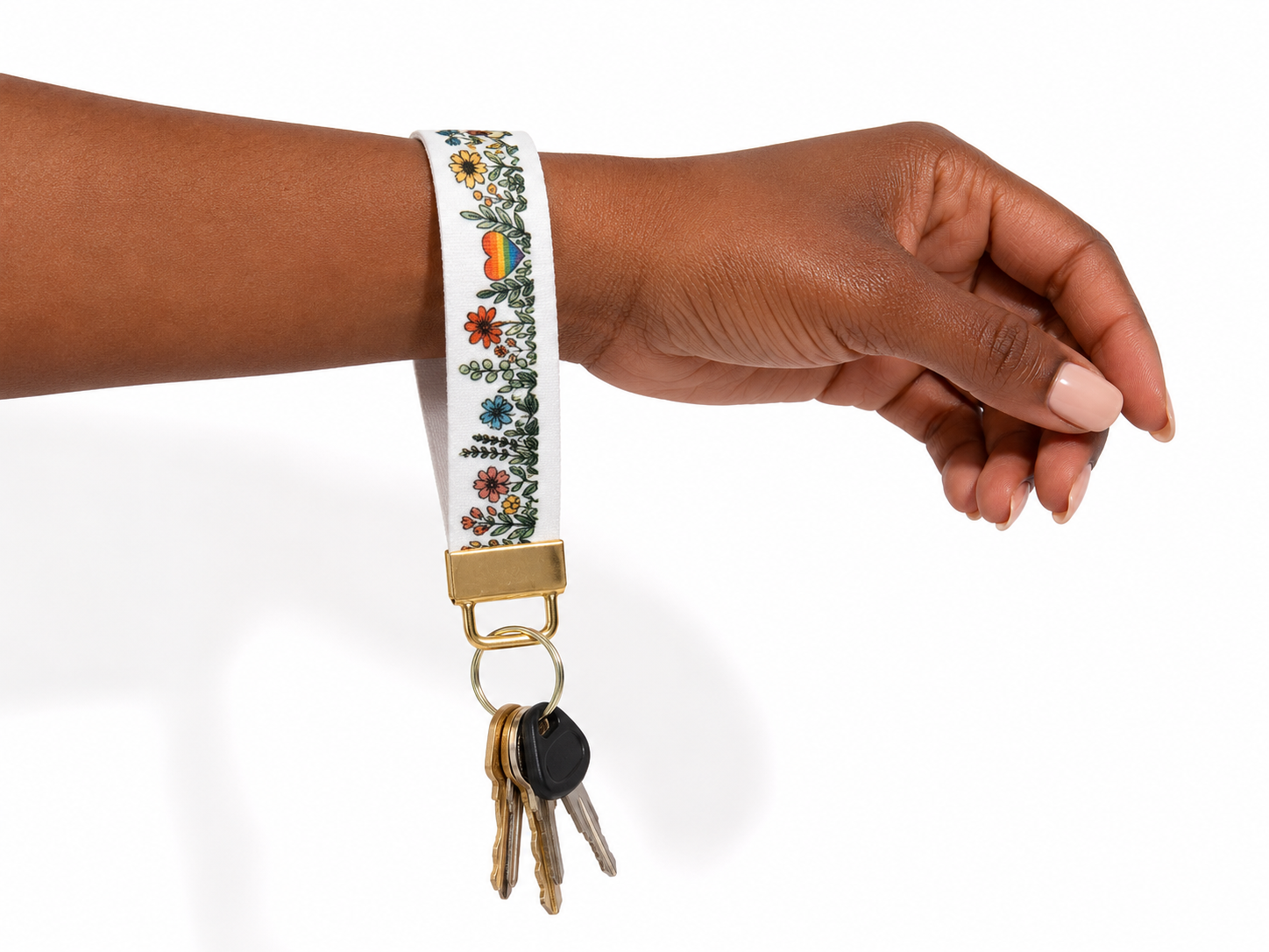 Hand wearing a floral keychain with keys on a white background