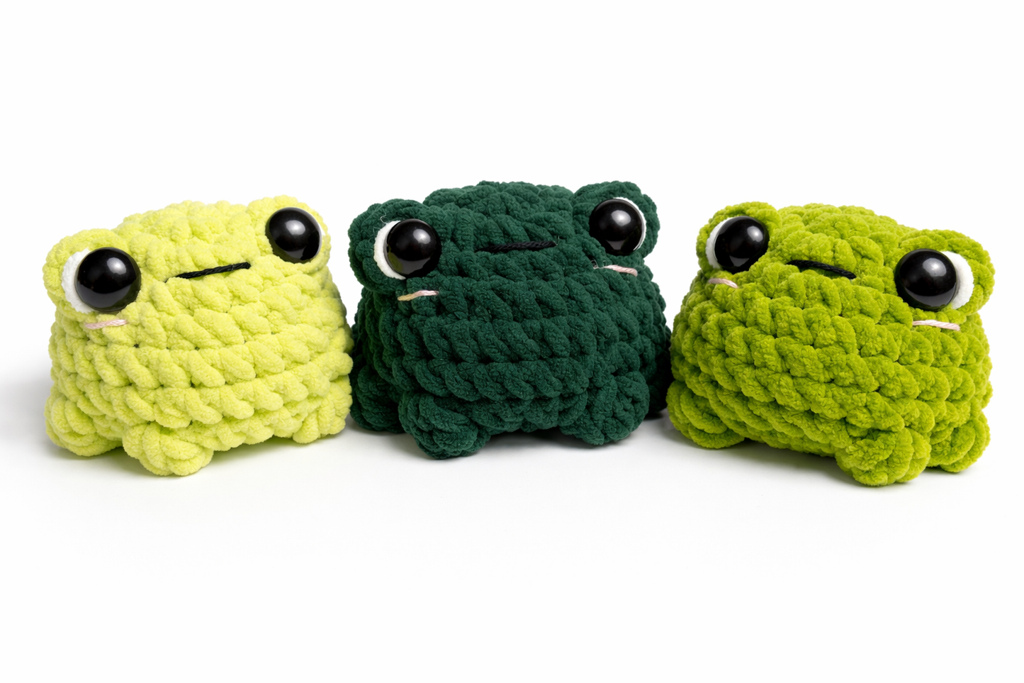 Three handmade crochet frog plushies shown together in pale green, deep green, and bright green.