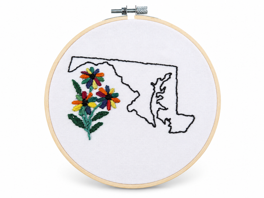Embroidery hoop with a map of Maryland and colorful flowers on a white background