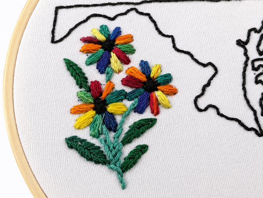Embroidery hoop with colorful floral design on a white background