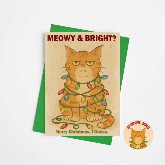 Funny orange cat Christmas card with coordinating green envelope showing grumpy cat tangled in Christmas lights with sarcastic holiday message
