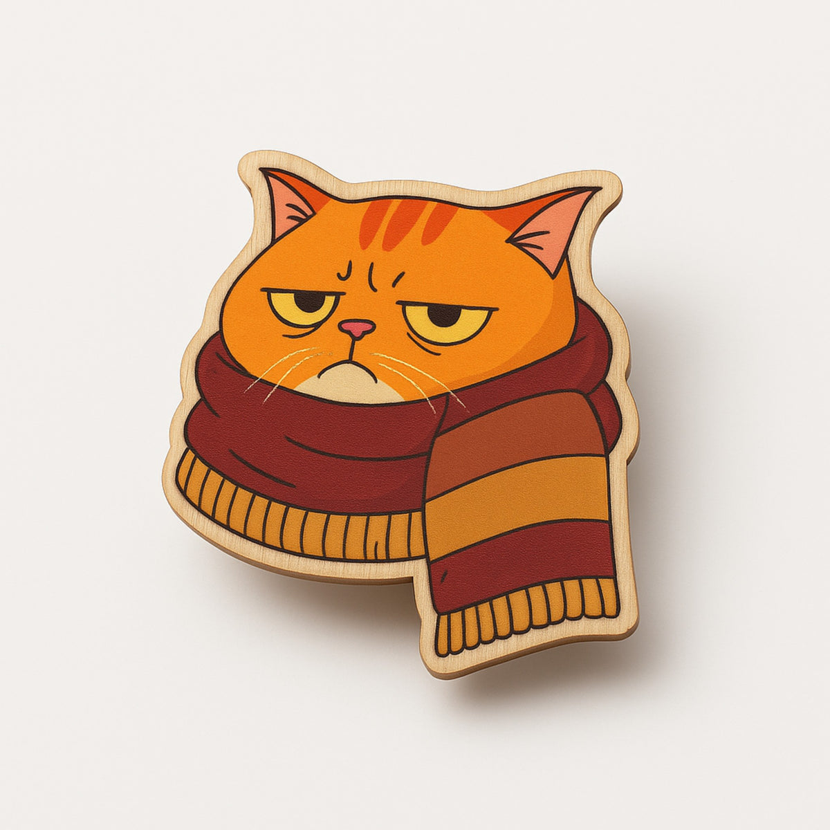 Cat-shaped brooch with a striped scarf on a light beige background
