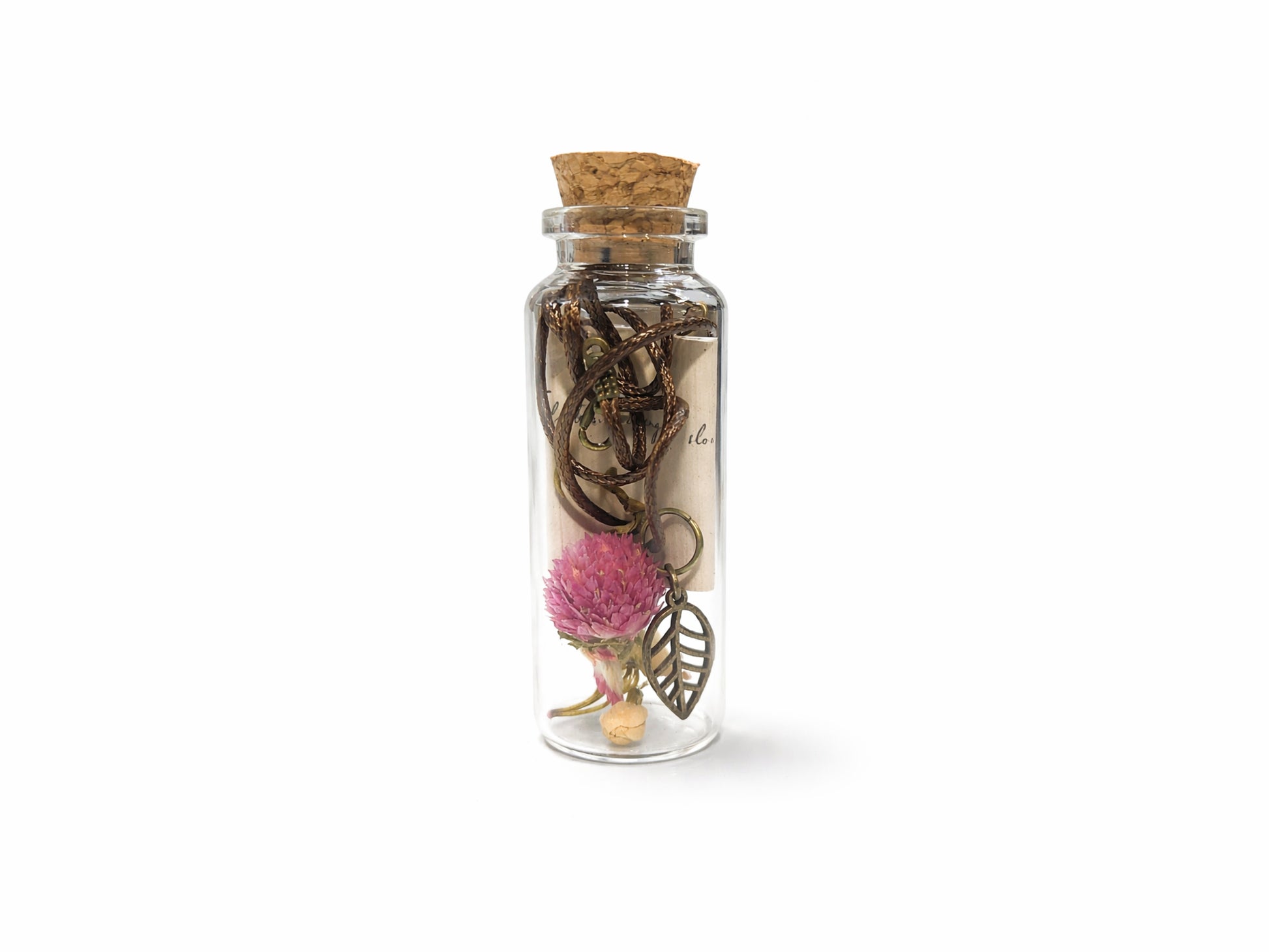 Small glass jar with cork lid containing decorative items on a white background