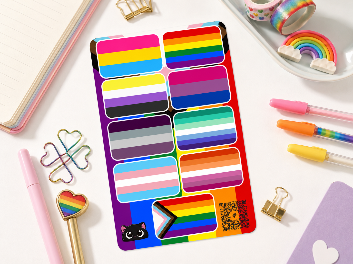 Colorful sticker sheet with rainbow and gender pride designs on a desk with stationery items.