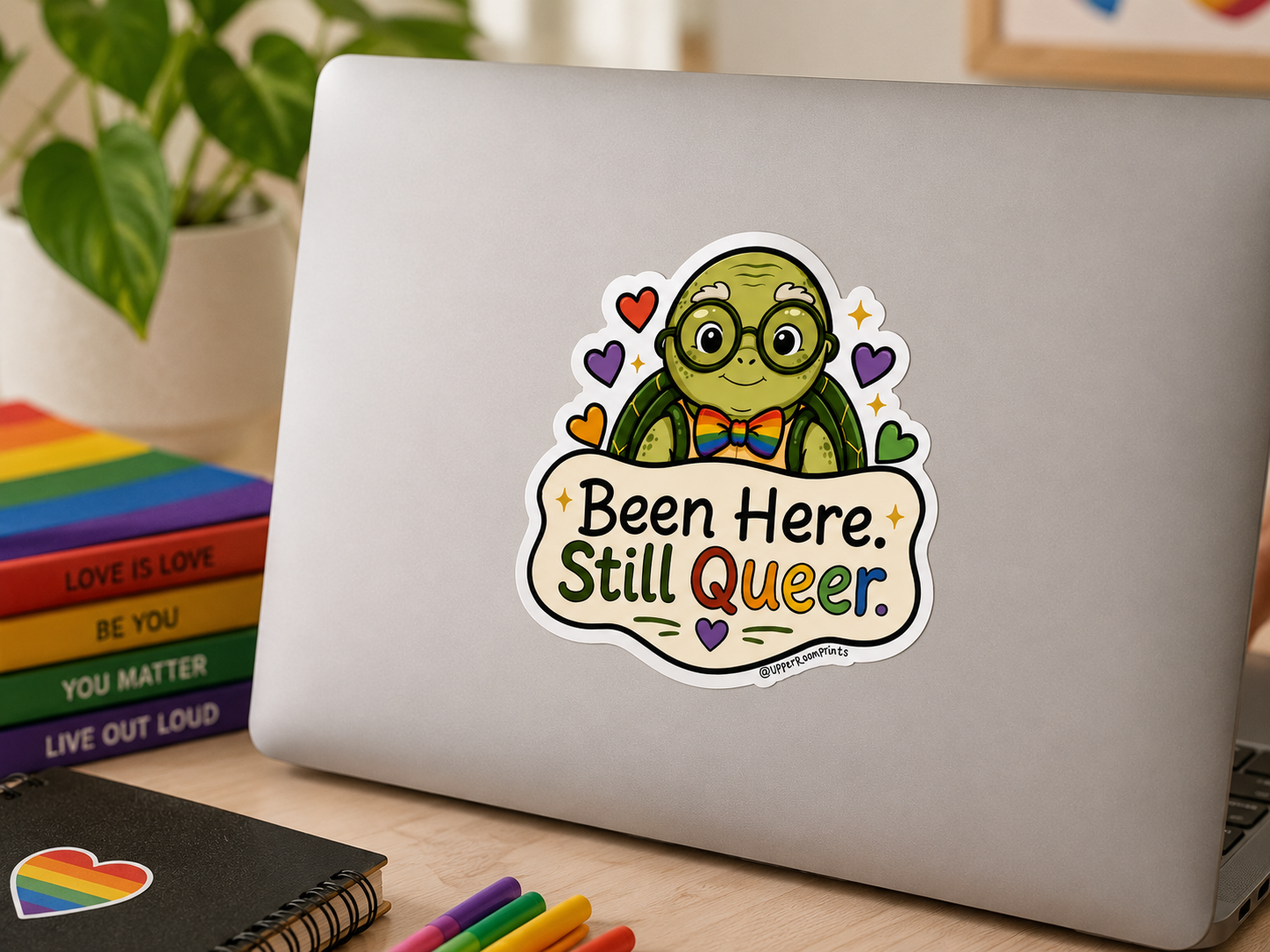 Laptop with a sticker on a desk with books and stationery
