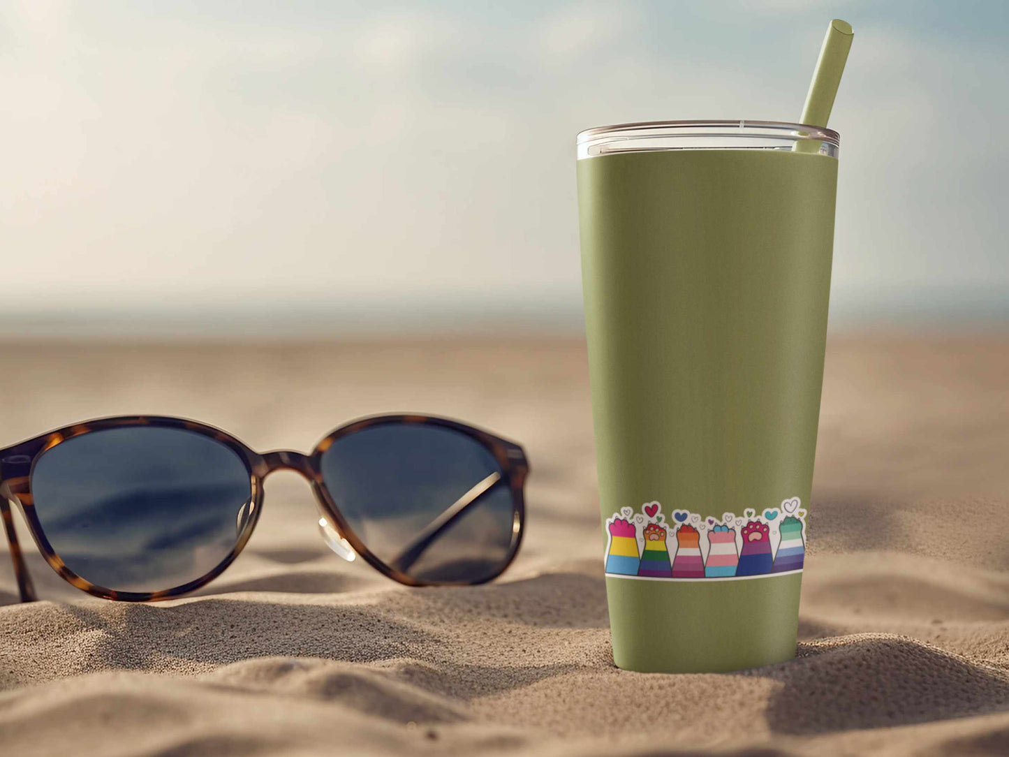 Alphabet Mafia kitty sticker applied to green tumbler, showing rainbow cat paw flags on a beach with sunglasses nearby