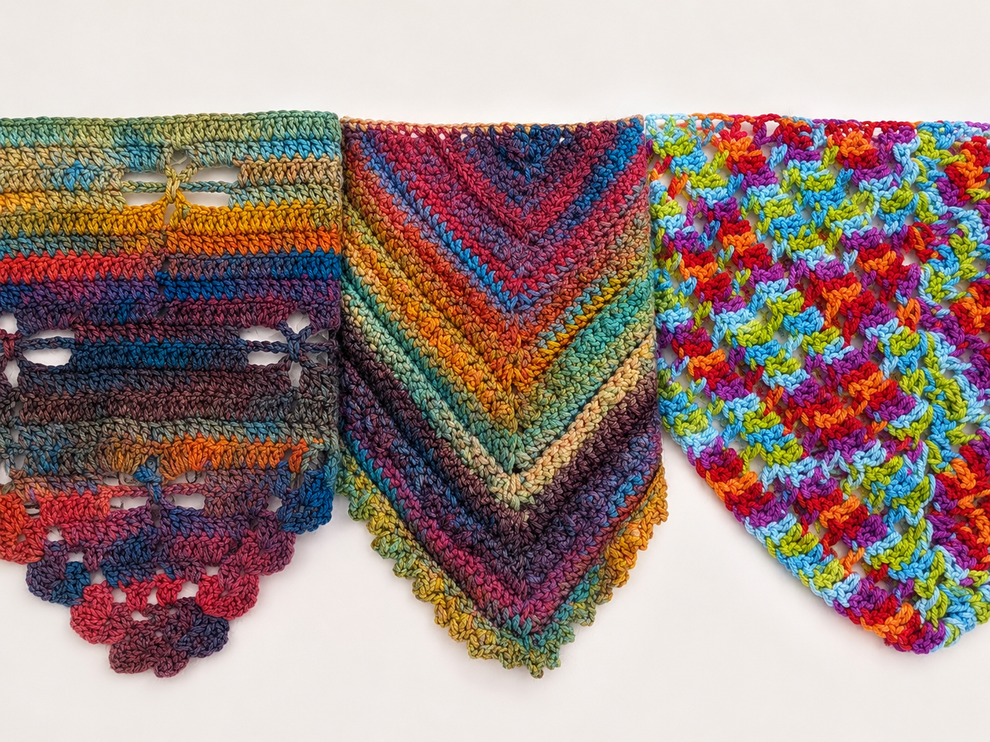 Colorful crocheted shawls with different patterns on a white background