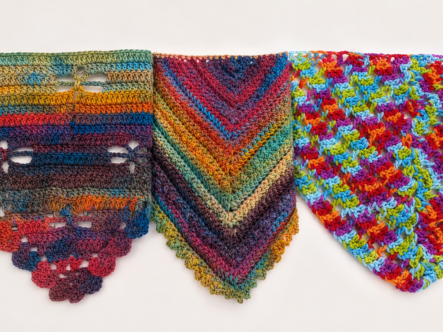 Colorful crocheted shawls with different patterns on a white background