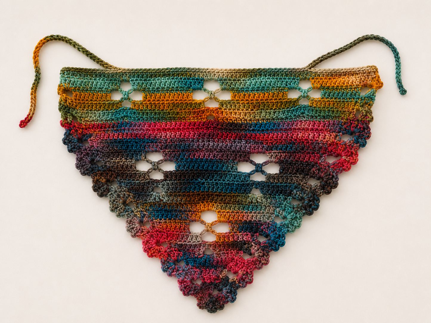 Multicolored crocheted triangle scarf on a white background
