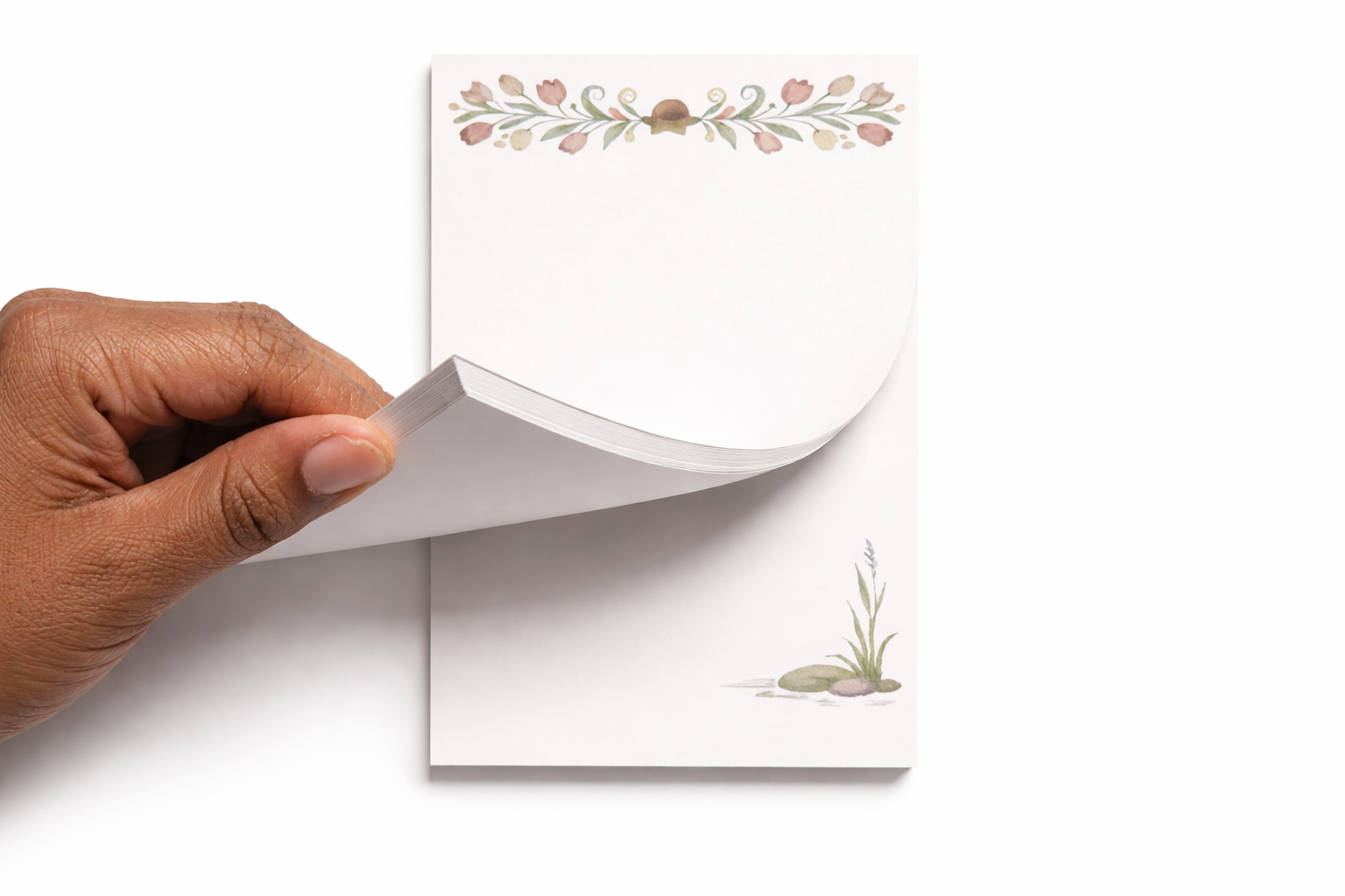Hand holding a stack of white cards with floral designs on a white background