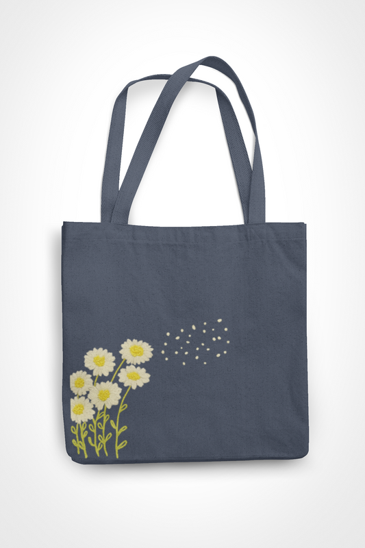 Hand-embroidered charcoal gray canvas tote bag featuring white and yellow daisies with floating petals, showing detailed needlework craftsmanship
