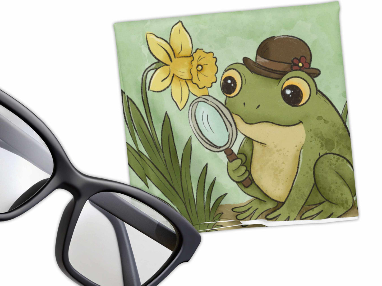 Cute frog in a bowler hat examining a daffodil with a magnifying glass on a green microfiber cloth