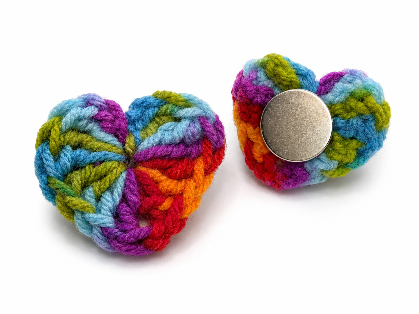 Colorful knitted heart-shaped toy with a metal button on a white background