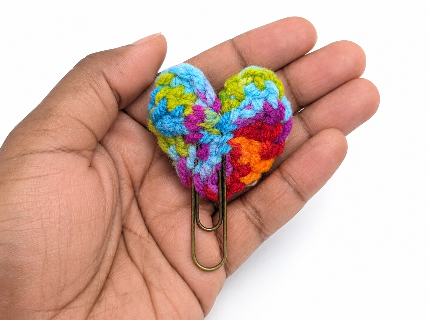 Colorful crocheted heart held in a hand with a white background