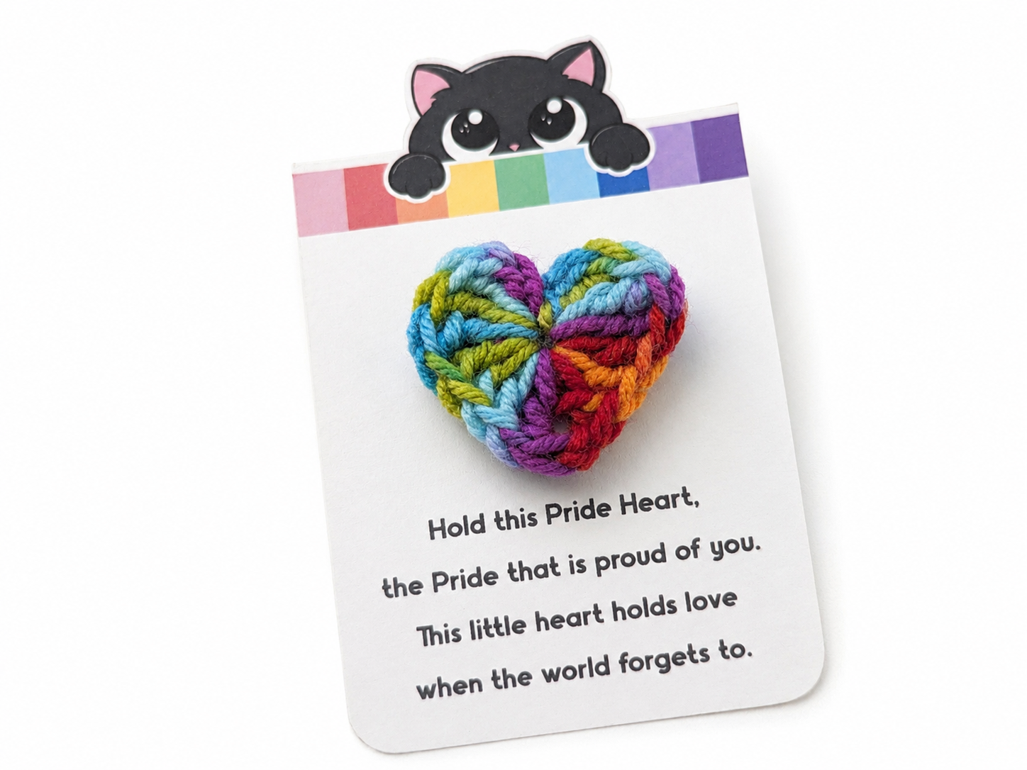 Colorful knitted heart on a card with text and a cat-shaped magnet on a white background