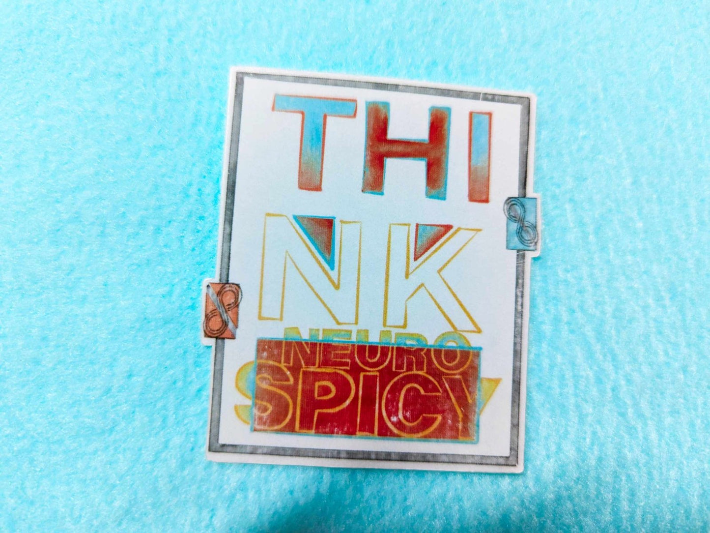 Close-up of the Think Neurospicy Sticker, a clear waterproof and weatherproof vinyl decal with bold text design.