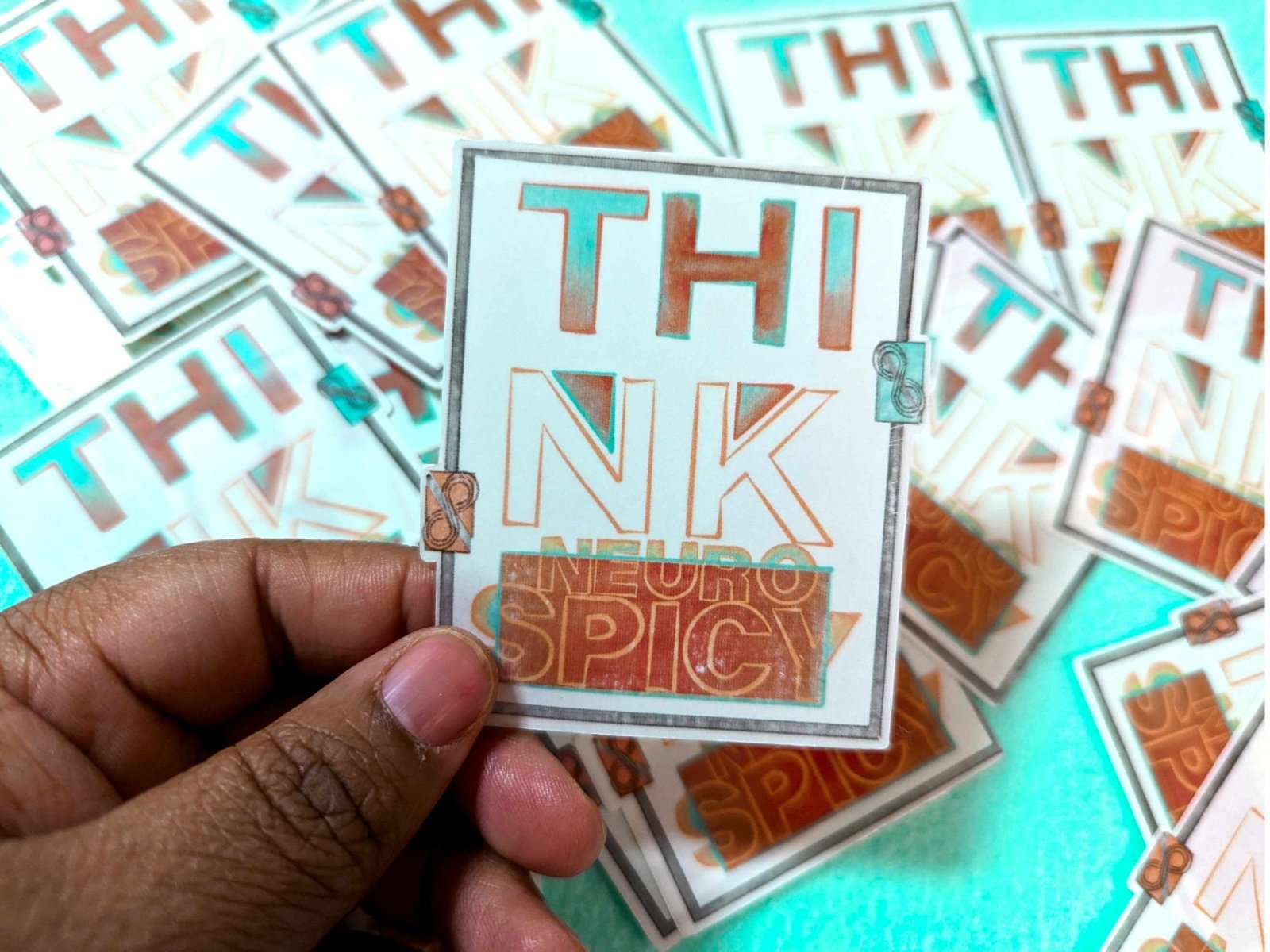 Think Neurospicy Sticker being held between fingers, showcasing its clear vinyl design and compact 3-inch size.