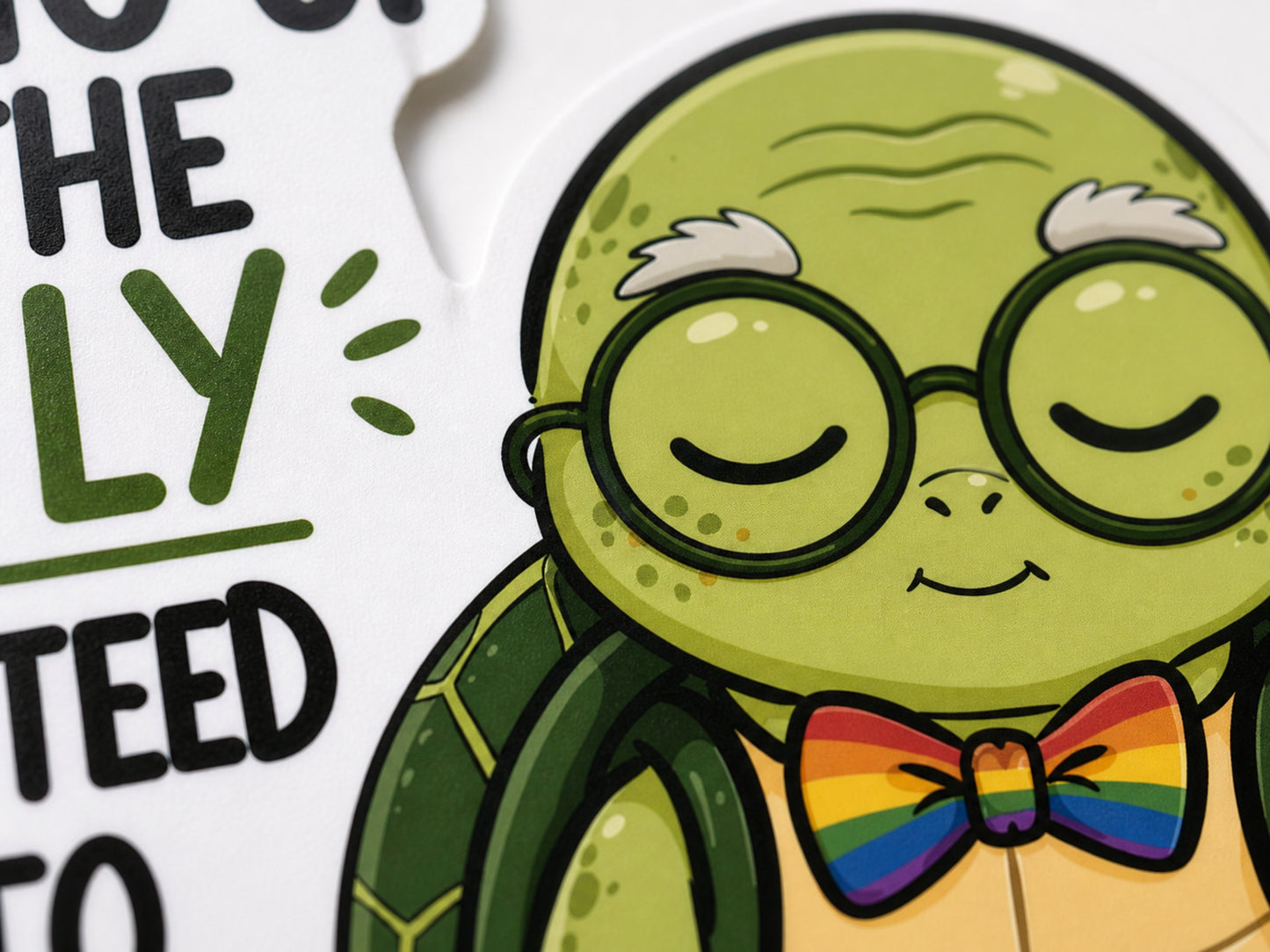 Close up of Wilbur turtle sticker showing glasses, smiling face, and rainbow bow tie next to the quote text