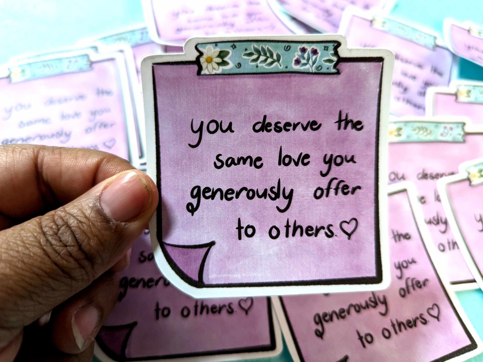 You Deserve Sticker held in hand, featuring a motivational message and a lavender design on waterproof vinyl material